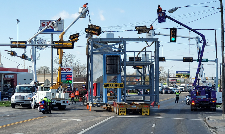 Patrol officers and utility workers help a semi move an oversize load