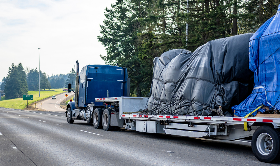 A flatbed truck carries tarped cargo