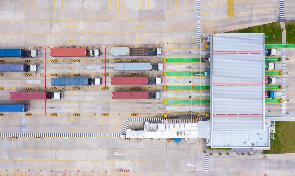 Semi trucks wait in queue to enter a port and pick up freight shipments