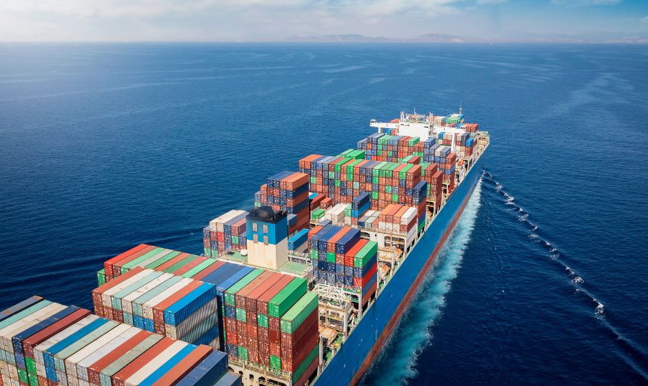A large ship carrying freight containers crosses a wide blue sea