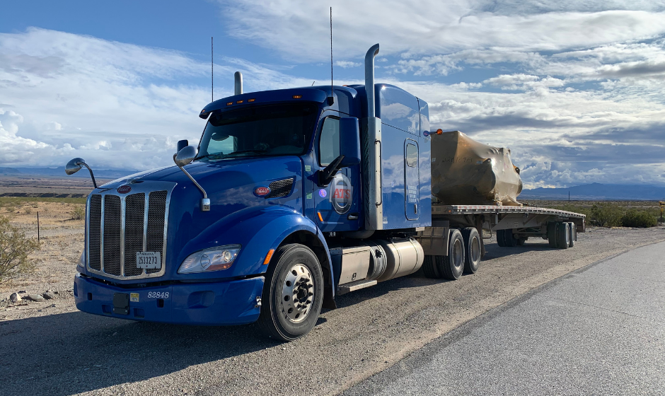 An ATS truck carrying freight on a flatbed trailer