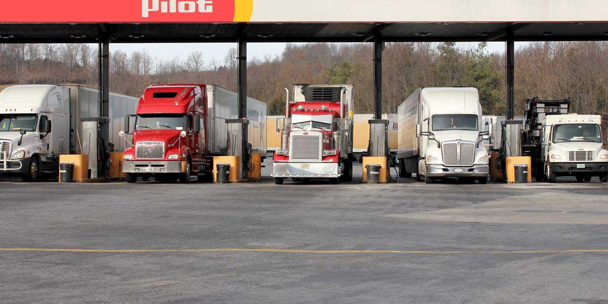 Semi-trucks lined up at Pilot truck stop getting diesel.