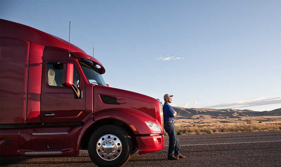Truck-driver-leaning-on-red-semi-truck