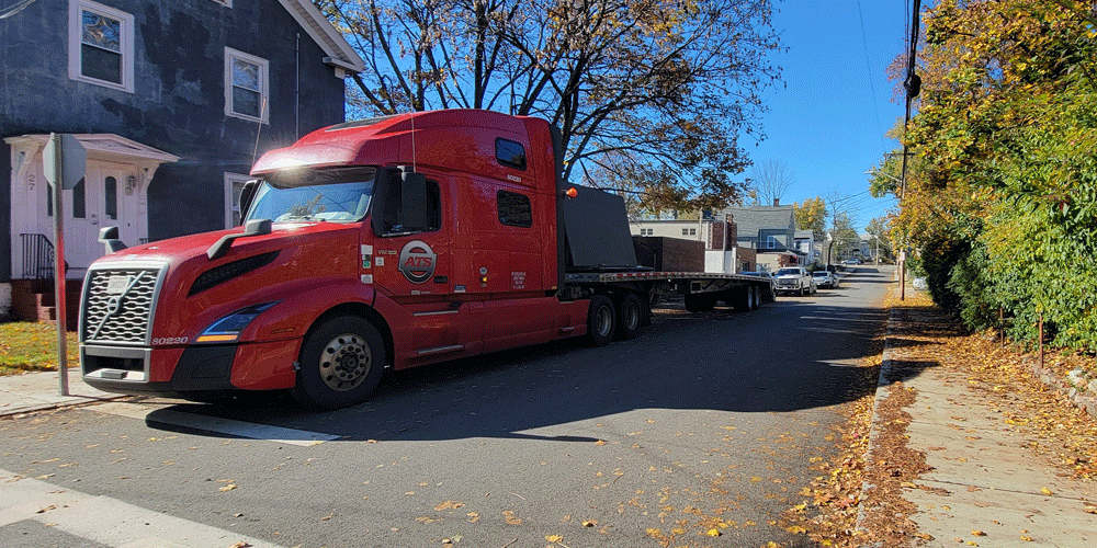 Semi-truck parked at a home on a narrow street.