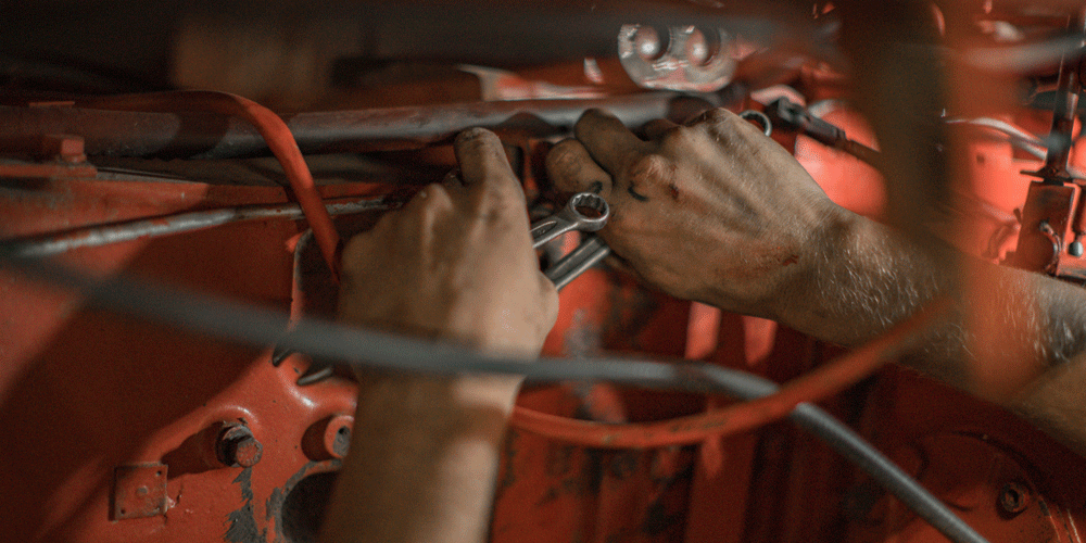 Close-up of a mechanic's hands wiring a truck part.