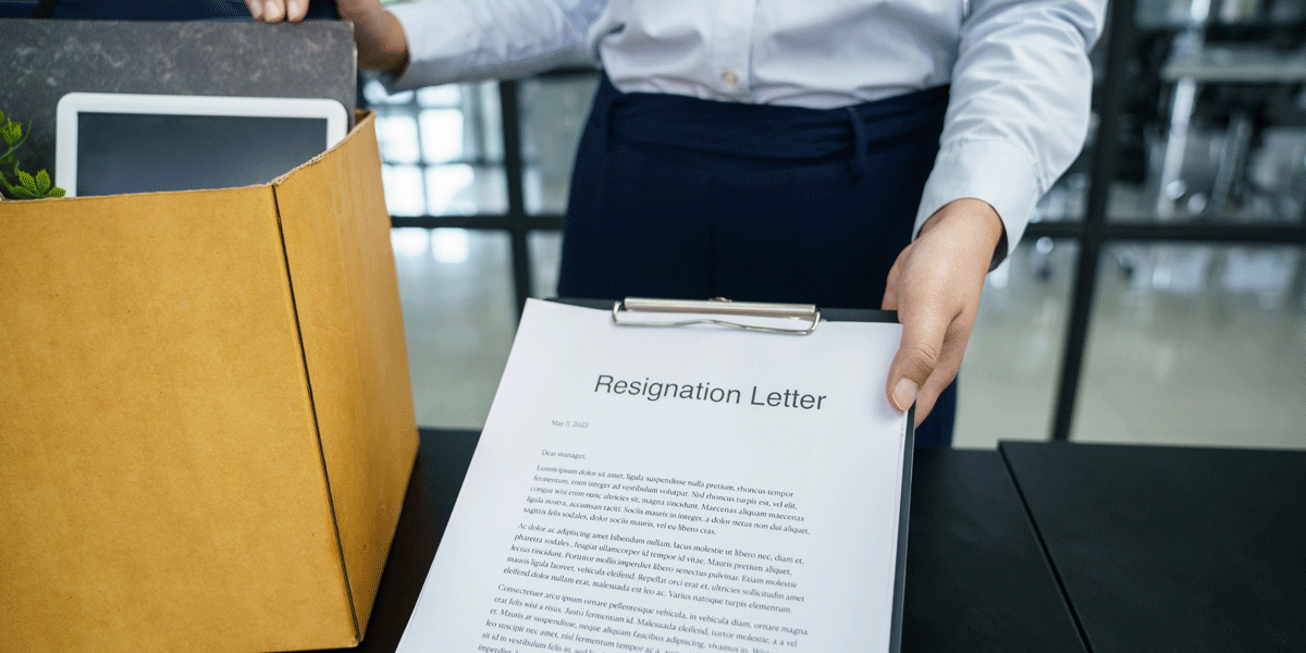 A person holding a clipboard with a typed up resignation letter on it.