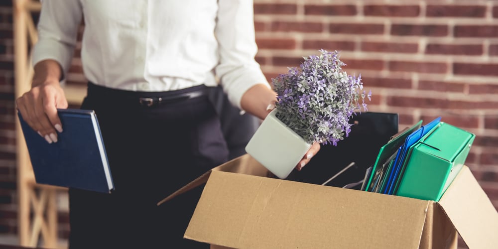 Woman putting work items in box after getting laid off