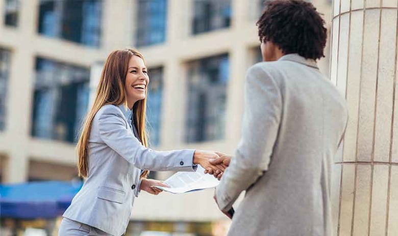 Female salesperson shaking hands with client outside office building