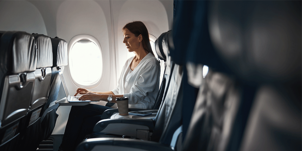 Woman working on her laptop on a plane.