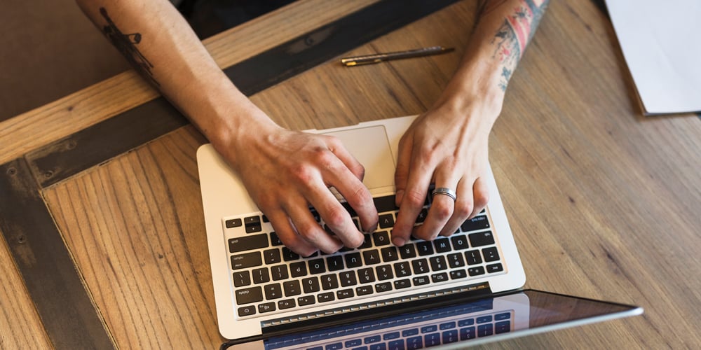 Person with tattoos working at a laptop