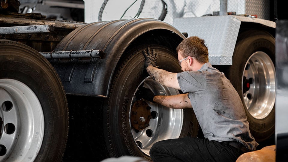 Mechanic-fixing-drive-tire-on-semi-truck