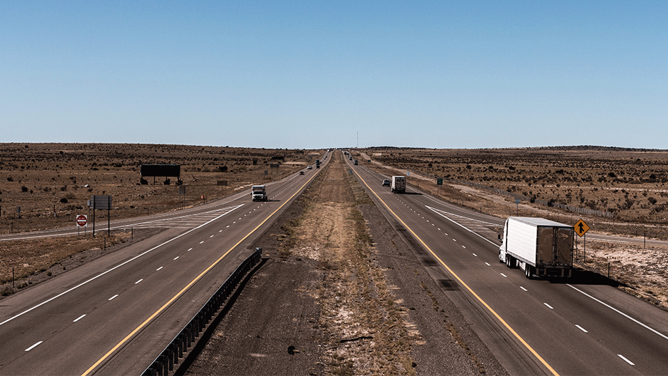 Trucks travel on a highway in the desert