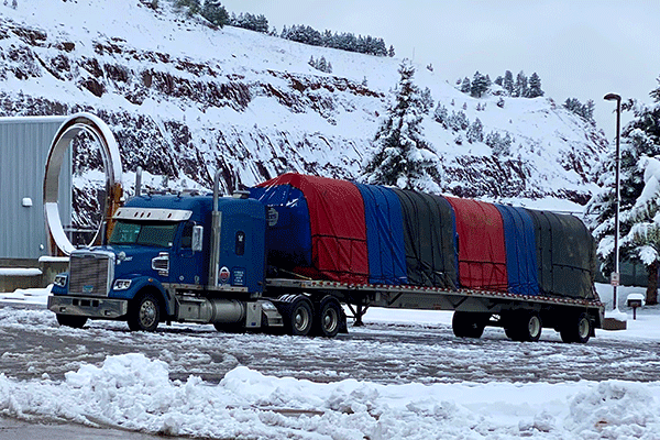 A truck hauling a tarped flatbed load in the winter