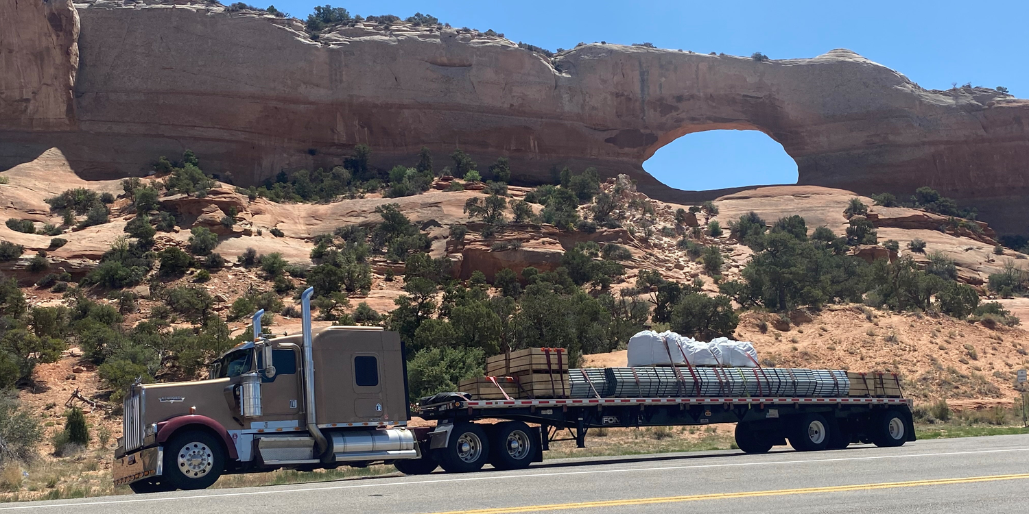 Tan flatbed truck sitting by rock formation