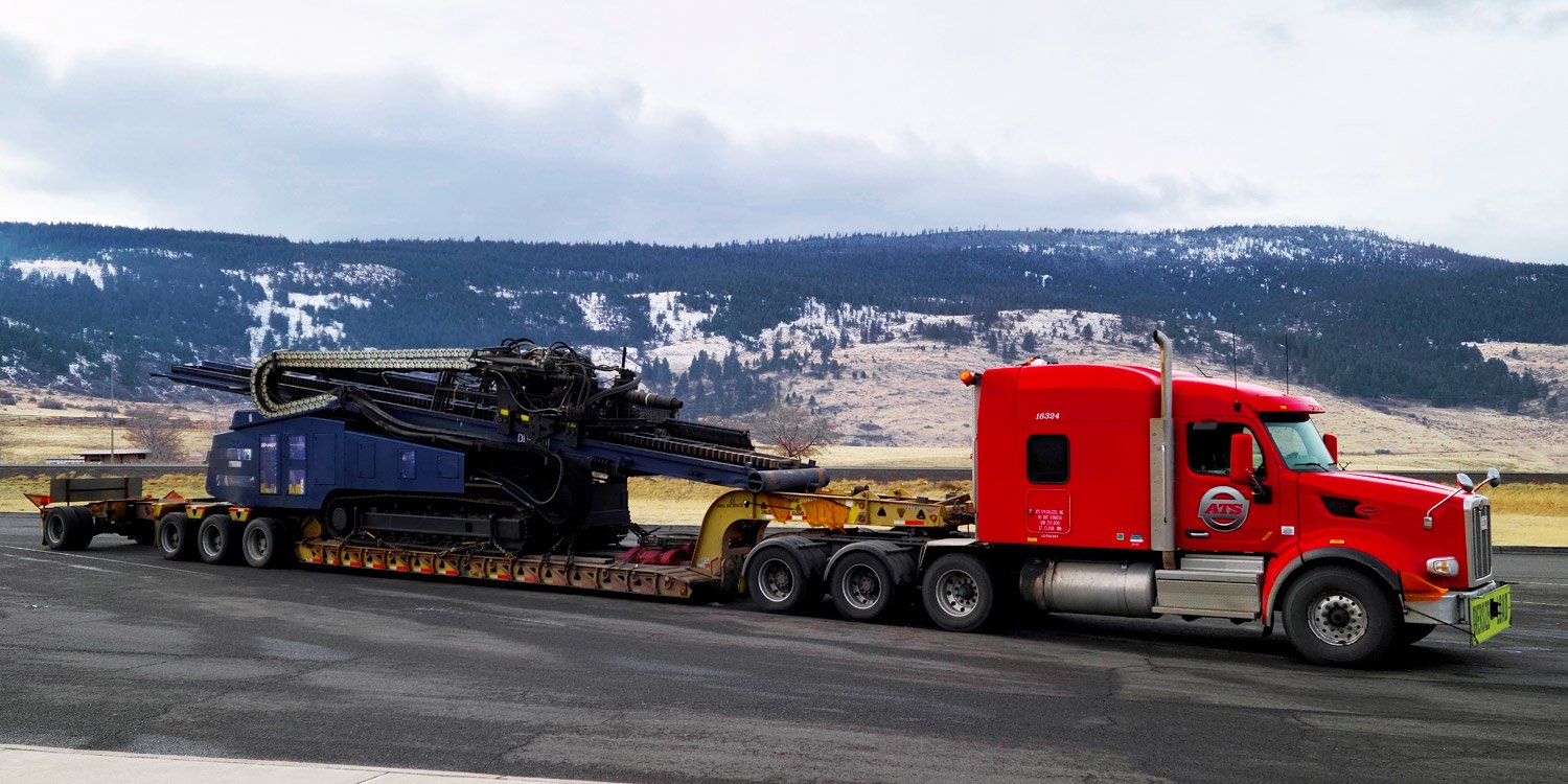 8-axle heavy haul truck parked in lot with mountains in the background