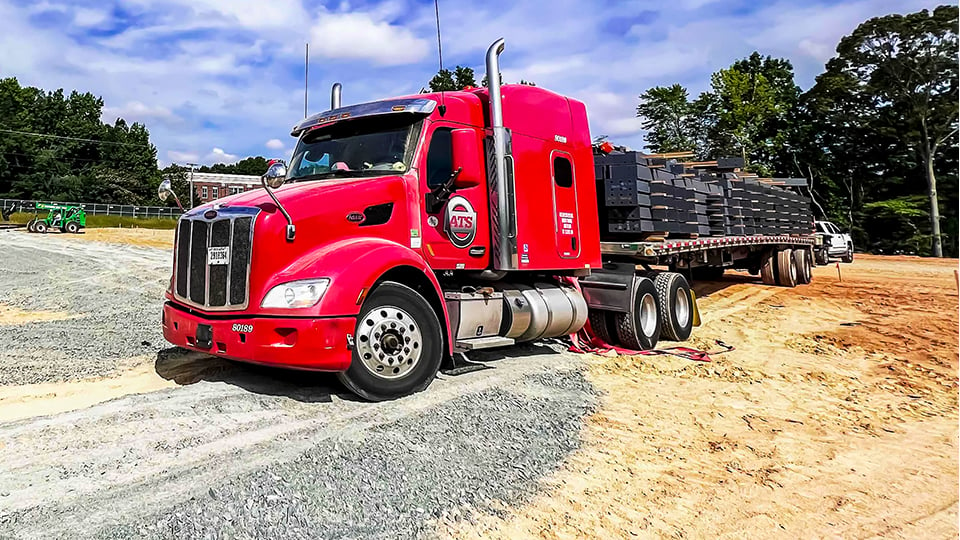 Red truck with flatbed trailer at jobsite