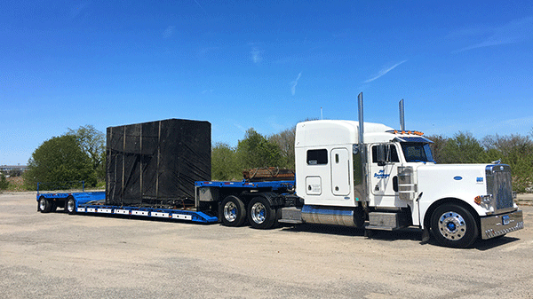 A large shipment travels on a specialized open deck trailer