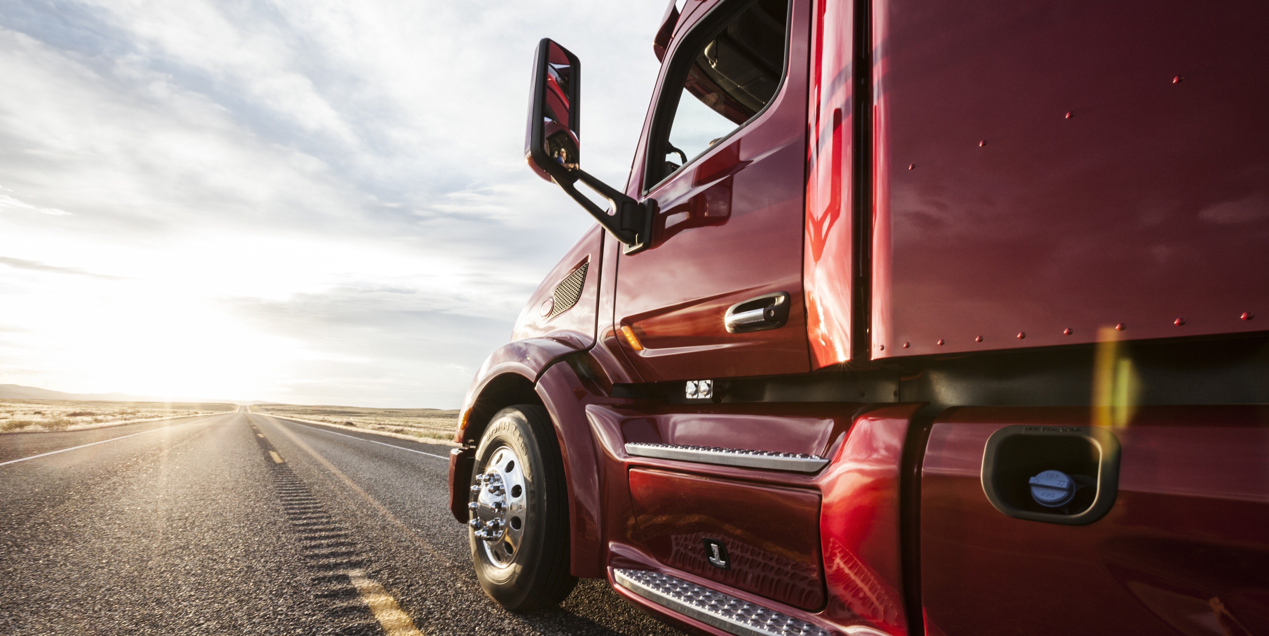 close up side view of american semi truck driving down a highway in the summer