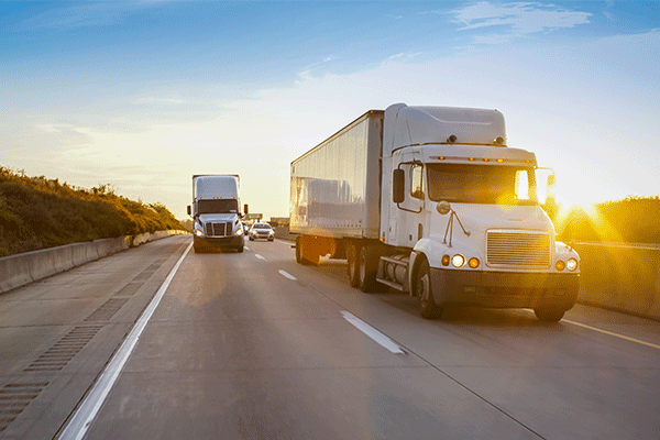 Trucks travel on a highway at sunset
