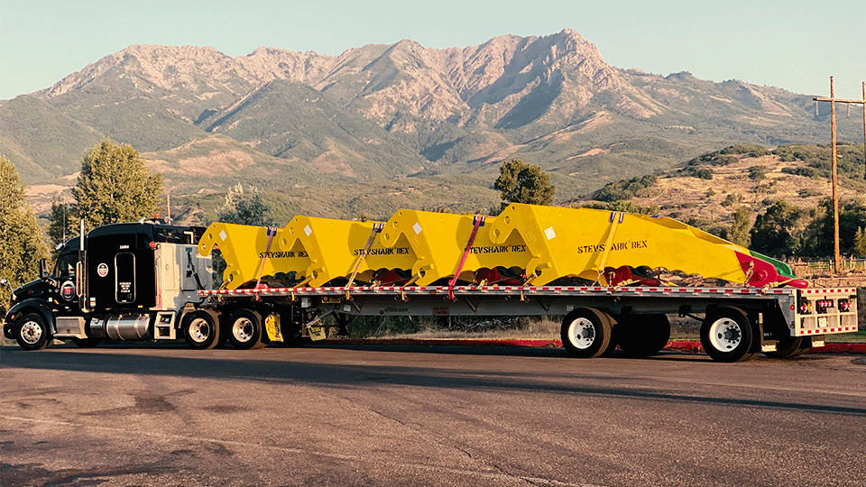 Spread axle flatbed parked in front of mountains