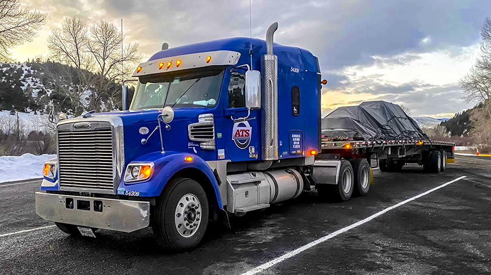 Blue tractor with tarped flatbed load