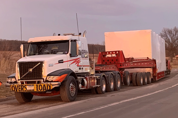 A truck hauls a piece of heavy equipment for a data center logistics project