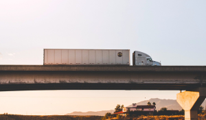 A semi truck with dry van trailer crosses an overpass