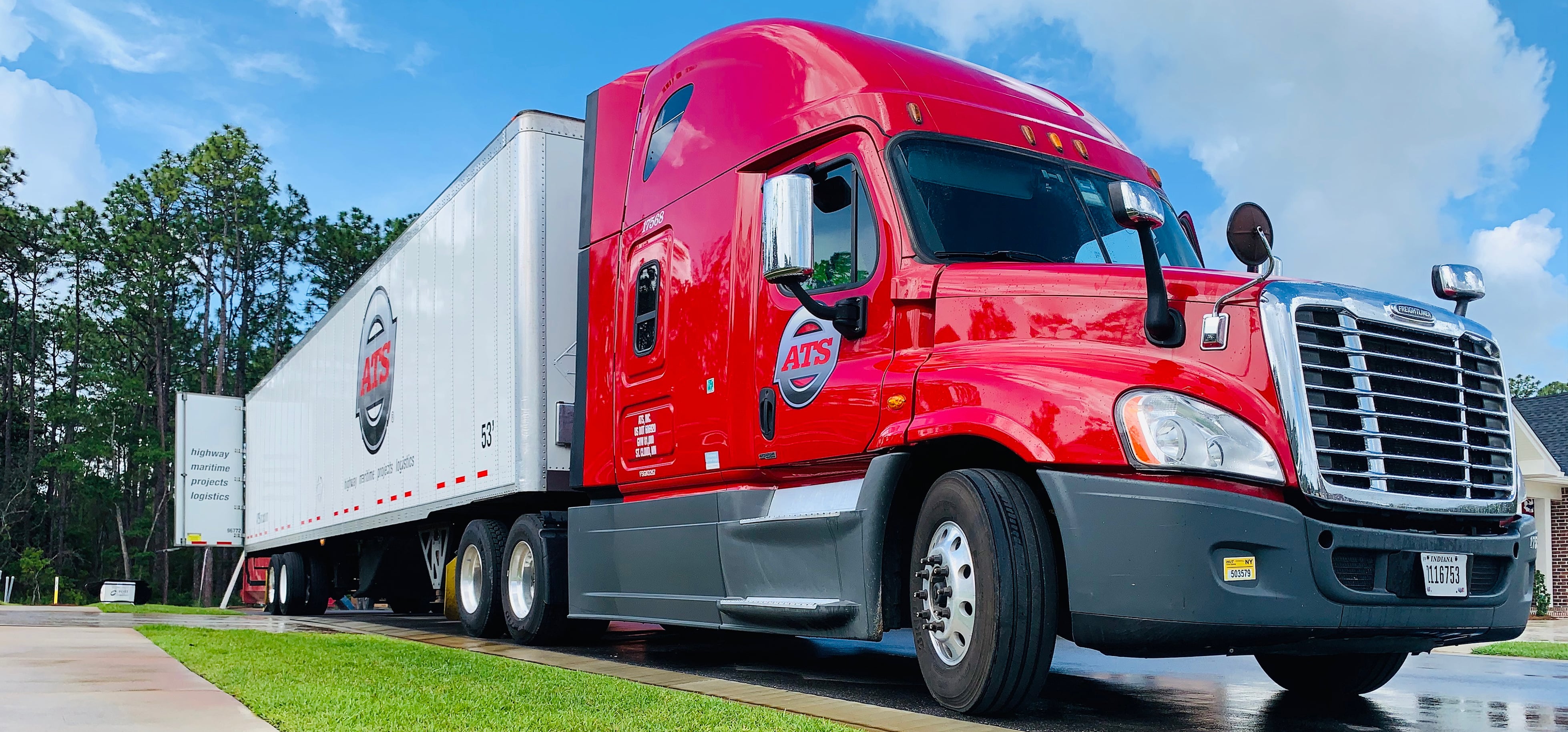 An ATS truck hauling a dry van trailer with its back doors open for unloading
