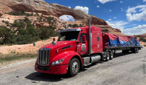 An ATS flatbed truck carrying cargo through a desert mesa.